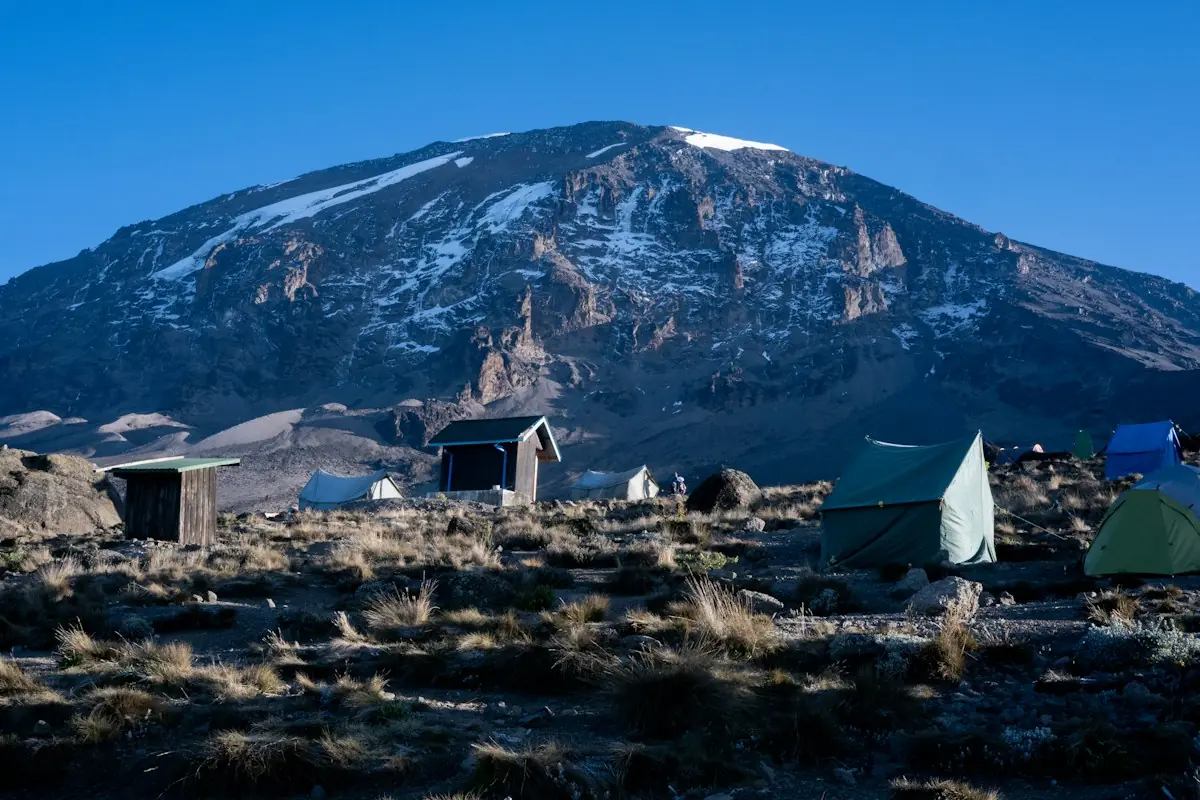 Tents pitched on rocky ground below a snow-capped summit