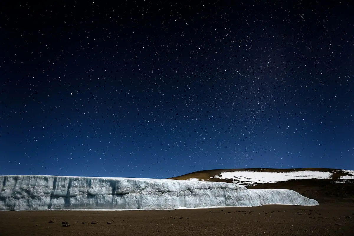 A glacier wall glowing under a sky full of stars