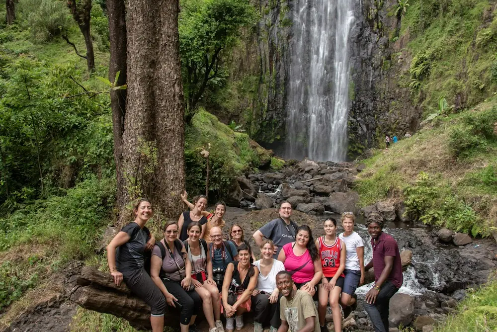A smiling group posing in front of a forest waterfall