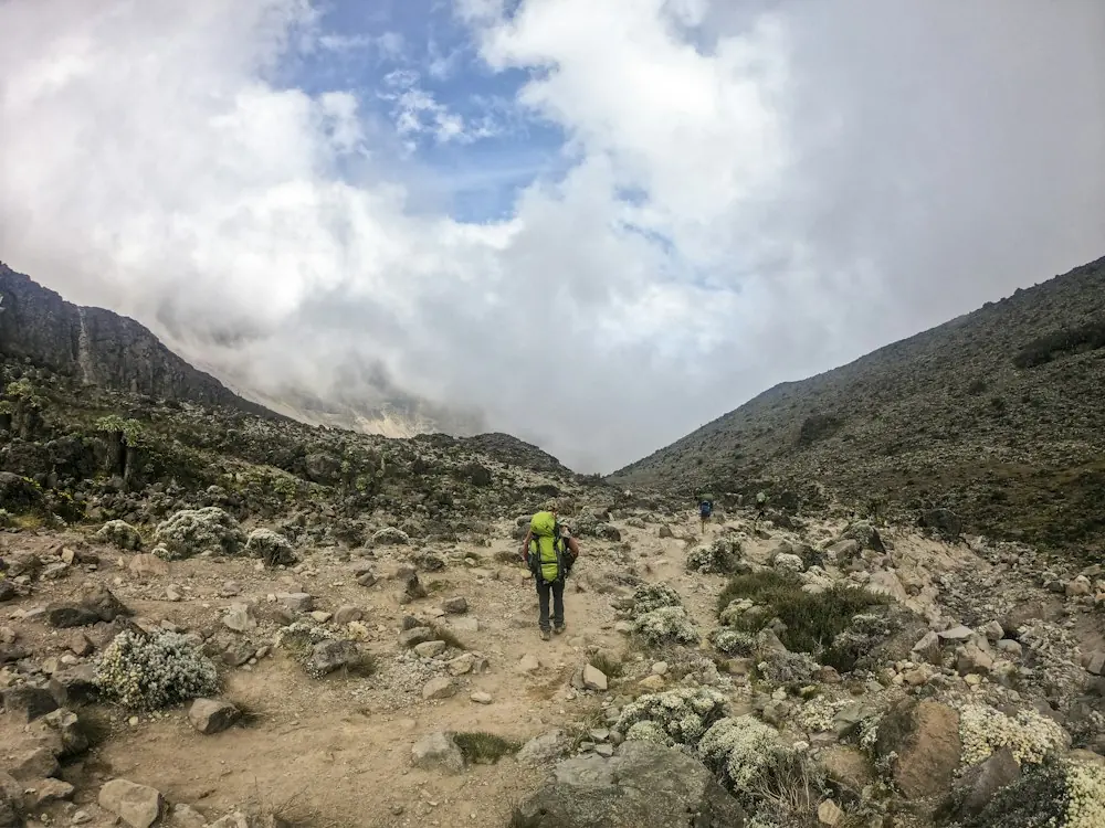 A lone hiker on a rocky trail as cloud rolls through the valley